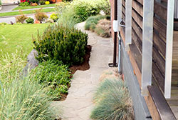 The side garden, too narrow for fencing (that would obstruct views as well), is fun with a zig-zag to the paving and low, soft grasses and perennials.