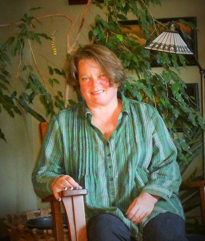 Kelly Carter Mortimer, owner and designer at Big Picture
    Landscape, sits in her home surrounded by houseplants.